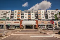 Modern apartment complex with retail storefronts below, under a clear blue sky, offering urban convenience and stylish living.