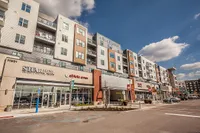 Contemporary mixed-use building showcasing modern apartments above vibrant retail spaces under a clear blue sky.
