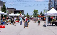 Vibrant summer block party with lively crowds, colorful tents, and festive decorations under a sunny sky.