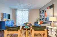 Contemporary living room with a stylish blue sofa, bold abstract art, and natural wood furniture, creating a cozy and inviting atmosphere.