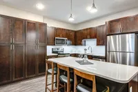 Modern kitchen with sleek stainless steel appliances, rich wooden cabinetry, and an elegant island with seating.