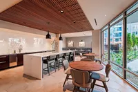 Modern communal area with sleek kitchen, elegant seating, and large windows offering garden views for a serene living experience.