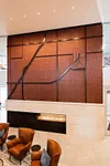 Luxurious lobby with elegant wood panel wall art and cozy modern seating by a sleek linear fireplace.