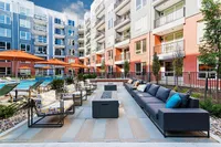 Modern apartment complex with vibrant outdoor seating area, sleek fire pit, and inviting pool, perfect for relaxation and entertaining.