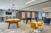 Vibrant and modern recreation room with a pool table, foosball, and chic seating area under stylish lighting.