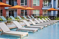 Elegant poolside lounge area with modern chaise lounges and vibrant orange umbrellas, perfect for relaxation and leisure.