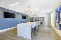 Modern dining area with sleek white table, contemporary lighting, and vibrant blue accent wall in a stylish apartment.