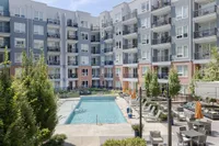 Modern apartment complex with a luxurious outdoor swimming pool, surrounded by lush greenery and stylish lounge areas, perfect for relaxation and social gatherings.