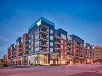 Modern apartment building with stylish balconies and vibrant brick facade at sunset, offering urban living at its finest.