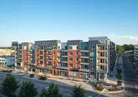 Modern mid-rise apartment building with vibrant brick facade, balconies, and street-level retail space at The Vue.