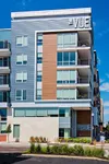 Modern apartment building with sleek design, large windows, and spacious balconies at The Vue, set against a bright blue sky.
