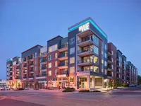 Modern apartment building at dusk, showing vibrant architecture with illuminated balconies and spacious design.