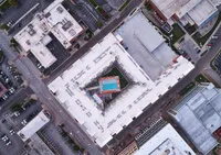Aerial view of a modern apartment complex featuring a lush central courtyard with a sparkling pool, surrounded by vibrant cityscape.