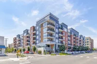 Modern apartment building 'The Vue' with stylish balconies and vibrant urban setting under a clear blue sky.