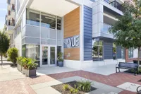 Modern apartment building entrance at The Vue, featuring sleek architectural design with large windows and vibrant greenery.