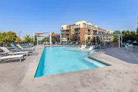 Inviting outdoor pool area with luxurious lounge chairs and shaded seating, perfect for relaxation and social gatherings at a modern apartment complex.