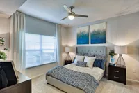 Elegant bedroom with a plush bed, modern decor, and natural light streaming through large windows. Features cozy bedside lamps and stylish wall art for a tranquil atmosphere.