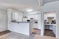 Modern kitchen with sleek white cabinetry, built-in appliances, and charming breakfast bar, ideal for contemporary living.