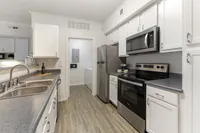 Modern kitchen with sleek stainless-steel appliances, elegant white cabinetry, and stylish wood flooring.