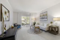 Inviting living room with elegant decor, showcasing a plush white sofa, chic coffee table, and modern artwork, perfectly lit by natural sunlight through large windows.