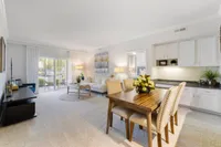 Bright and inviting open-concept living and dining area featuring elegant furnishings, large windows, and a modern kitchen layout.