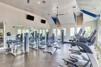 Bright, contemporary gym featuring top-of-the-line exercise equipment, mirrored walls, and large windows for natural light.