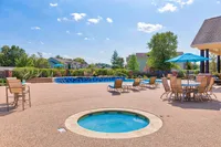 Vibrant outdoor pool area with loungers and umbrellas, surrounded by lush greenery and modern architecture.