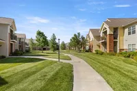 Charming apartment complex with manicured lawns and inviting pathways under a bright blue sky.