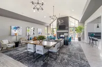 Luxurious open-concept living room with modern decor, elegant chandeliers, and a cozy fireplace, perfect for entertaining.