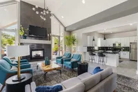 Contemporary open-plan living area with elegant decor, featuring a cozy seating arrangement around a modern fireplace and a sleek kitchen with high-end appliances.
