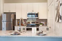 Modern kitchen with elegant white cabinetry, stainless steel appliances, and a chic marble countertop, perfect for culinary enthusiasts.