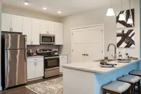 Modern kitchen with stainless steel appliances, sleek white cabinetry, and a chic breakfast bar featuring contemporary pendant lighting.