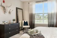 Cozy bedroom with chic decor, featuring contemporary furniture, stylish wall art, and a large window with a scenic view.