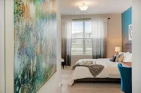Inviting bedroom with a cozy bed, stylish decor, and a large window providing ample natural light.