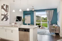 Modern kitchen and living area with sleek design, granite countertops, stylish lighting, and large windows offering a scenic garden view.