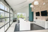 Contemporary open-concept lounge with stylish brick walls, modern kitchen island, and expansive window views in upscale apartment.