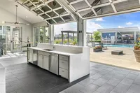 Modern open kitchen with sleek appliances leading to a sunlit patio and swimming pool view.