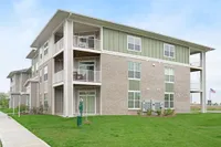 Modern three-story apartment building with spacious balconies and well-maintained green lawn.