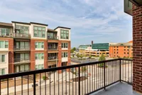 Modern urban balcony view featuring stylish red brick apartment buildings and a scenic cityscape in the background.