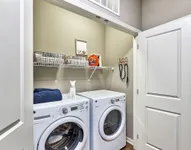 Charming laundry closet with modern washer and dryer, featuring elegant shelving for organized storage and delightful pet-themed decor.
