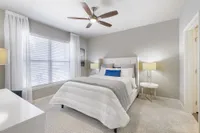 Elegant bedroom featuring a plush bed with stylish cushions, accentuated by soft lighting and a modern ceiling fan, creating a warm and inviting atmosphere.