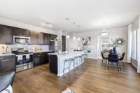 Elegant open kitchen with dark cabinetry, stainless steel appliances, and a stylish dining area with contemporary decor.