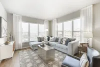 Bright and elegant living room with large windows, sleek sectional sofa, modern decor, and cozy ambiance.
