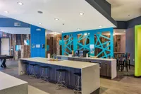 Chic and inviting communal space featuring a modern bar with sleek stools, vibrant blue accent walls, and stylish decor.