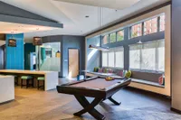 Modern recreational room with a sleek pool table, vibrant seating area, and stylish lighting.