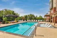 Luxurious apartment pool area featuring a vibrant lounge, stylish pergola, and inviting deck chairs for ultimate relaxation.