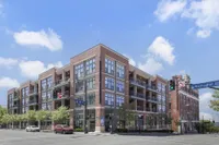 Contemporary red brick apartment building at the corner of Washington St and 12th St, featuring spacious balconies and large windows for abundant natural light.
