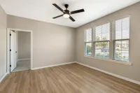 Bright and inviting room with elegant wood flooring, large windows, and a modern ceiling fan, perfect for a cozy living space.