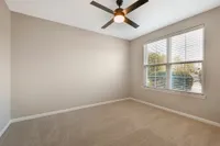 Bright and airy bedroom with neutral tones, a modern ceiling fan, and large window offering natural light and scenic views.