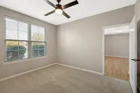Bright and airy room featuring plush carpet, large window with natural light, modern ceiling fan, and seamless transition to a stylish wooden floor.